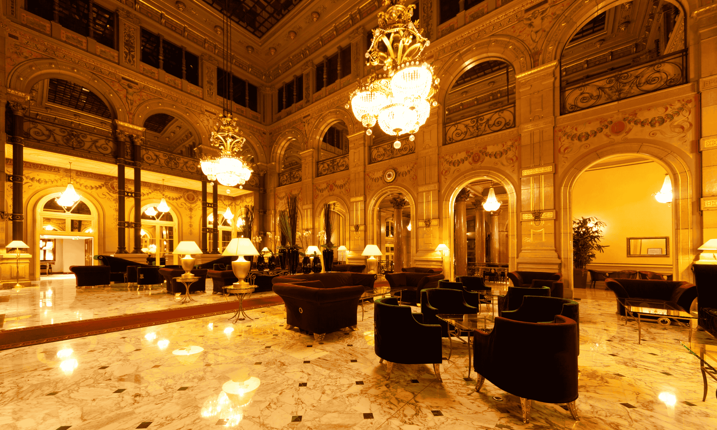 Opulent hotel lobby with marble floors, velvet armchairs, crystal chandeliers, and AI‑driven smart lighting, showcasing AI in Hospitality–powered guest personalization.